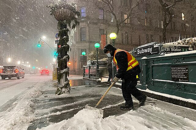 Workers clearing heavy snow from a New York City street after extreme winter weather.