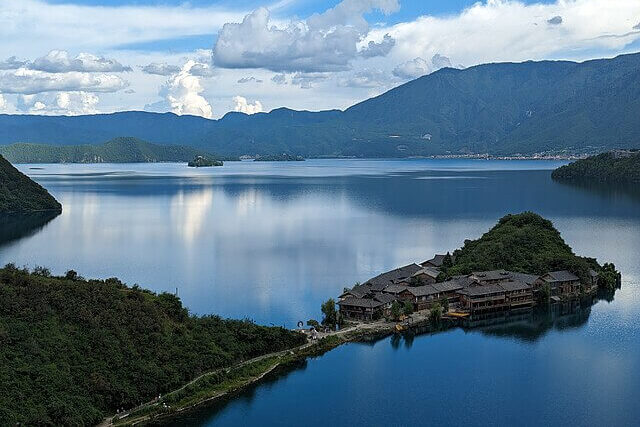 Lugu Lake in Yunnan, China, a freshwater lake surrounded by mountains and forested shoreline.