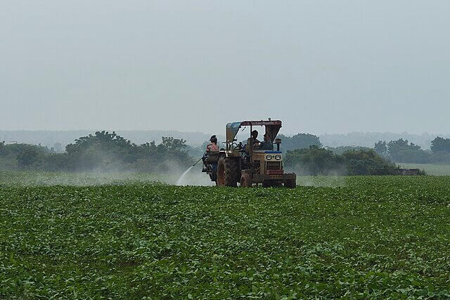 Farmer spraying pesticides on agricultural field to control crop pests and weeds