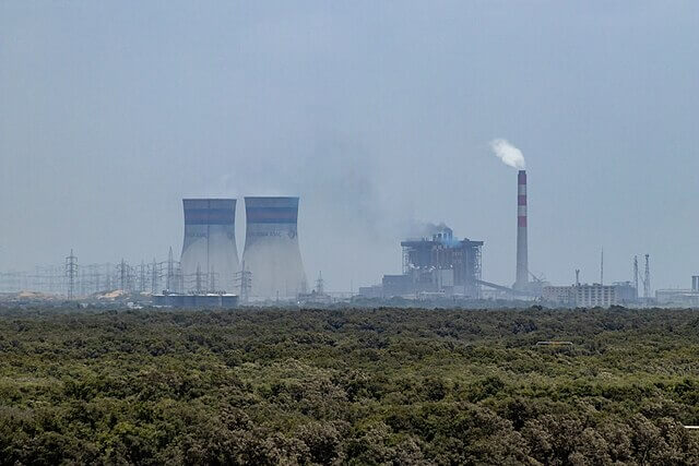 Coal-fired power plant releasing emissions, highlighting the role of fossil fuels in driving climate change.