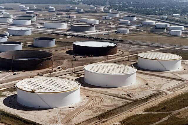 Crude oil storage tanks at an industrial facility, representing oil production and associated carbon emissions.