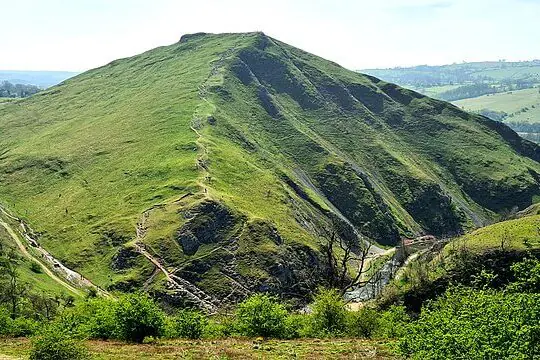 High-altitude landscape in the Peak District with rocky slopes and open moorland under wide sky