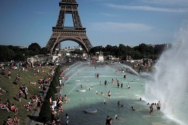 People paddling in water near the Eiffel Tower during hot weather in Paris