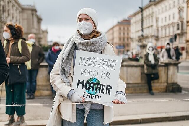 Crowd of climate change protesters holding placards and banners demanding urgent action on global warming and environmental protection.