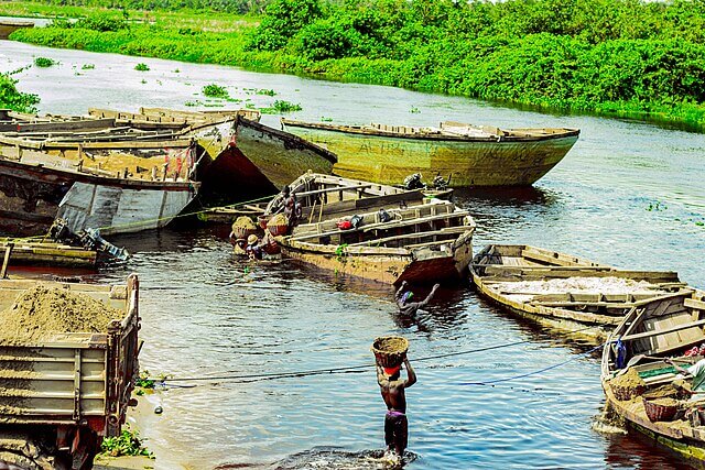 Artisanal sand miners hand dredging sand into small wooden boats in Lagos Lagoon, Nigeria, highlighting local livelihoods and environmental pressure