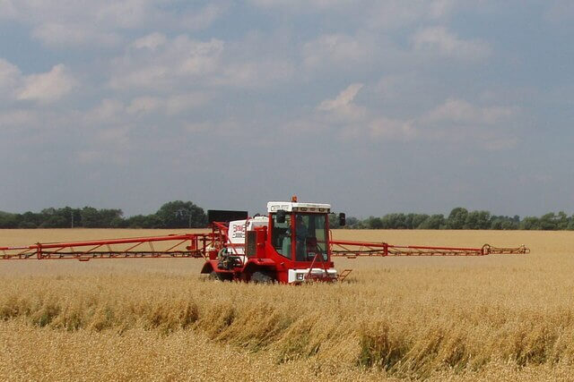 Farmer spraying glyphosate herbicide on UK farm field before harvest
