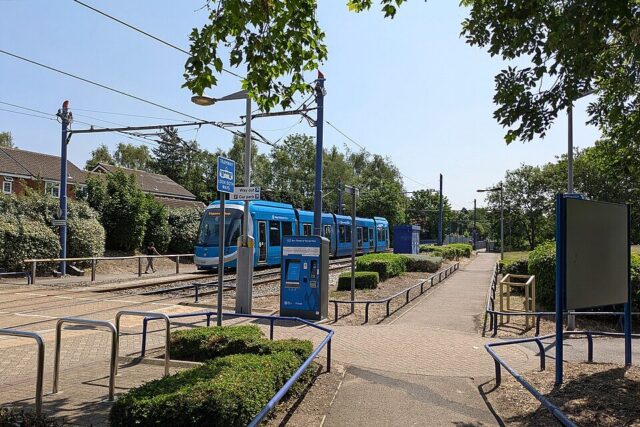 West Midlands Metro tram travelling through an urban area surrounded by newly planted wildflowers and green spaces.
