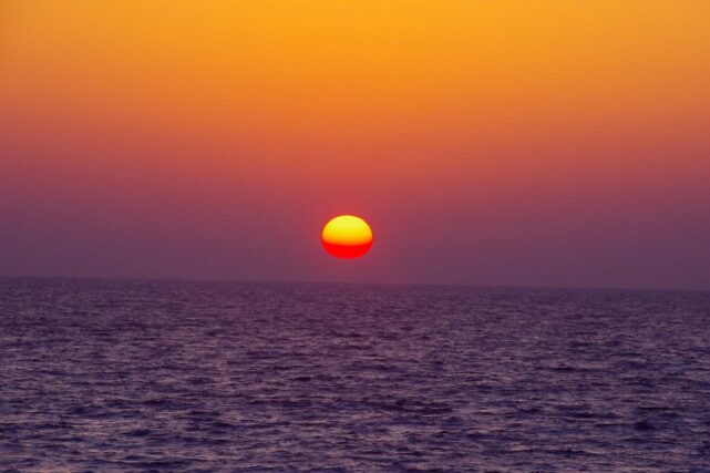 Hot sun setting over a warm ocean during a marine heatwave