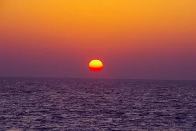 Hot sun setting over a warm ocean during a marine heatwave